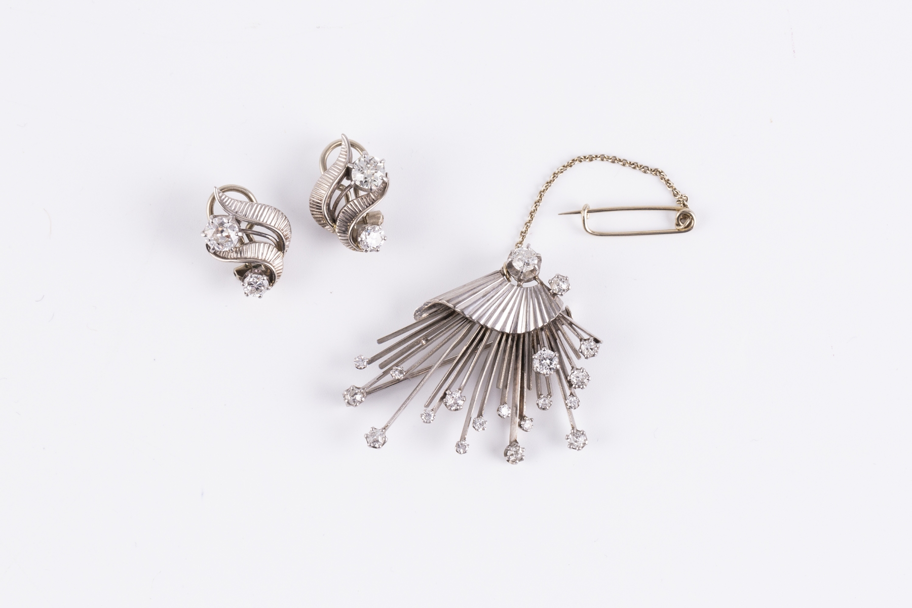 103- Une parure comprenant une broche en or gris sertie de petits brillants et une paire de clips d'oreilles. Adjugé 1300€