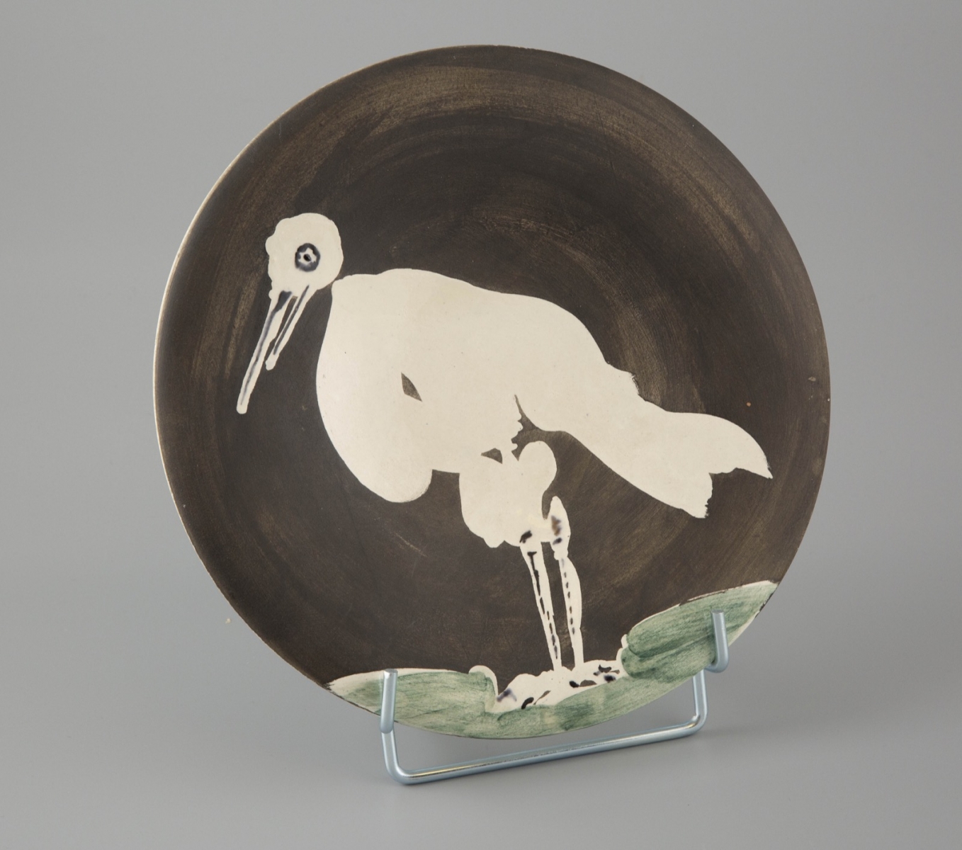61- Pablo Picasso-Madoura. Oiseau n°83. Assiette ronde en terre de faience blanche, l'engobe noire et verte. D.25cm. Adjugé 3200€